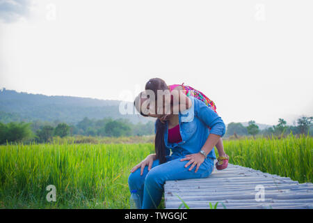 Heureuse Mère et son enfant à jouer à l'extérieur en s'amusant, champ de riz vert. Galerie d'images haute résolution. Banque D'Images