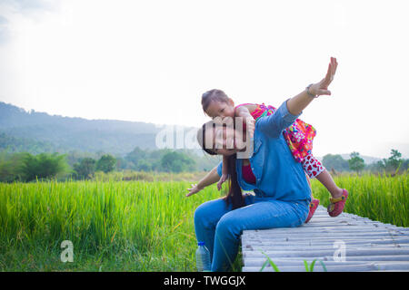 Heureuse Mère et son enfant à jouer à l'extérieur en s'amusant, champ de riz vert. Galerie d'images haute résolution. Banque D'Images