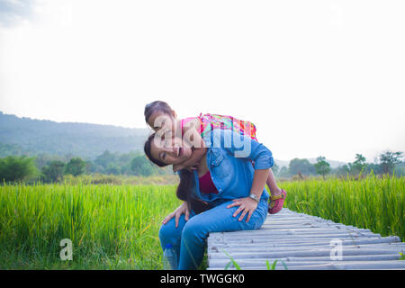 Heureuse Mère et son enfant à jouer à l'extérieur en s'amusant, champ de riz vert. Galerie d'images haute résolution. Banque D'Images