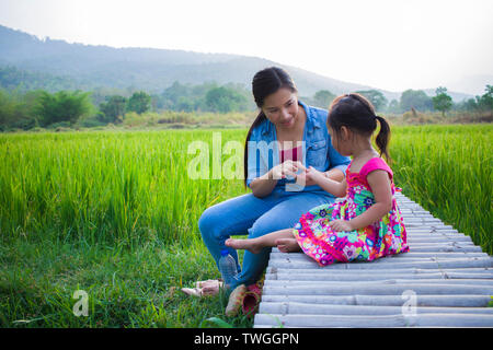 Heureuse Mère et son enfant à jouer à l'extérieur en s'amusant, champ de riz vert. Galerie d'images haute résolution. Banque D'Images