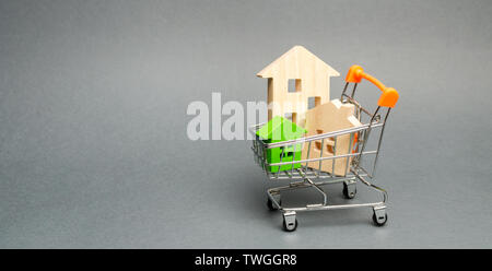 Maisons en bois dans un chariot de supermarché. Le concept de l'achat d'une maison ou appartement. Le logement à prix abordable. Rentables et des prêts bon marché de l'immobilier. Bu Banque D'Images