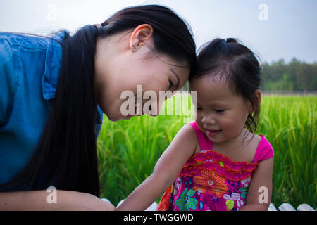 Heureuse Mère et son enfant à jouer à l'extérieur en s'amusant, champ de riz vert. Galerie d'images haute résolution. Banque D'Images