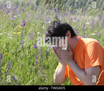 Jeune homme avec orange t-shirt blanc et d'éternuements au printemps Banque D'Images