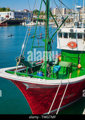 Un bateau de pêche amarré dans le port de Muelle del Hospitalillo Trintxerpe, avec quelques enfants kayak dans l'arrière-plan. Pasaia, Gipuzkoa, Espagne. Banque D'Images