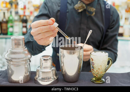 Barman se rendre au comptoir du bar à cocktails, l'ajout de certains dans le shaker amer Banque D'Images