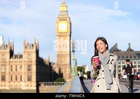 London femme heureuse par Big Ben rire et boire du café en automne. Jeune joueuse de Westminster Bridge, Londres, Angleterre. Belle jeune fille de race blanche asiatique multiraciale. Banque D'Images