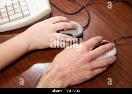 Frères jouent un jeu sur ordinateur. L'amour, les relations, la vie. Deux mains sur deux souris. Banque D'Images