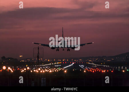 Avion de passagers à l'atterrissage à l'Aéroport International de Cape Town au crépuscule avec la piste d'atterrissage de toute évidence s'illuminèrent. Banque D'Images