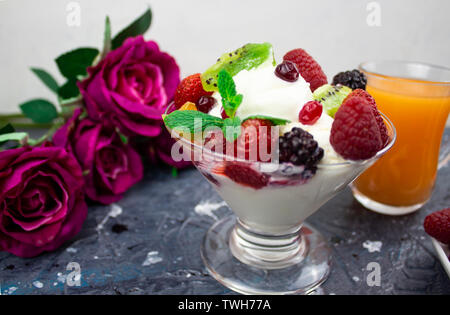 Dans un verre de jus de mandarine, crème glacée aux fruits rouges. contexte. roses Banque D'Images