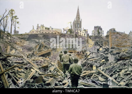 Patrouille d'infanterie américaine marche à travers les ruines de la ville française, après avoir été Saint-Lo, capturés dans les Allemands, Tour Sud de l'église de Notre Dame de Saint-Lo en arrière-plan, bataille de Normandie, France, Saint-Lo, Juillet 1944 Banque D'Images