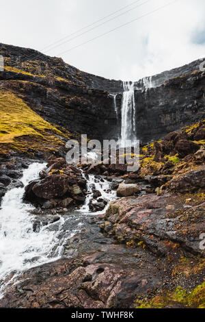 Fossa, la plus grande chute d'eau sur les îles Féroé, comme vu au début du printemps avec des pics de montagne couverte de neige et de luxueuse verdure (îles Féroé) Banque D'Images