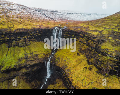 Des images aériennes de Fossa de cascade au-dessus, au début du printemps avec des pics de montagne couverte de neige et des tons verts (îles Féroé, Danemark) Banque D'Images