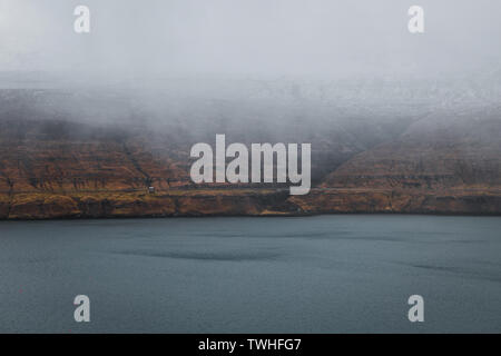 Typique du paysage des îles Féroé Moody vu de Fossa avec brouillard cascade basse dans les montagnes en face de la mer bleu foncé (îles Féroé) Banque D'Images