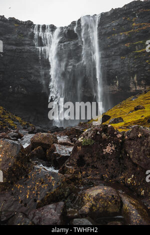 Fossa, la plus grande chute d'eau sur les îles Féroé, comme vu au début du printemps avec des pics de montagne couverte de neige et de luxueuse verdure (îles Féroé) Banque D'Images