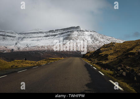 Vues road trip sur les routes sans fin sur les îles Féroé avec des pics de montagne couverte de neige, ciel bleu et nuages bas au printemps (îles Féroé) Banque D'Images