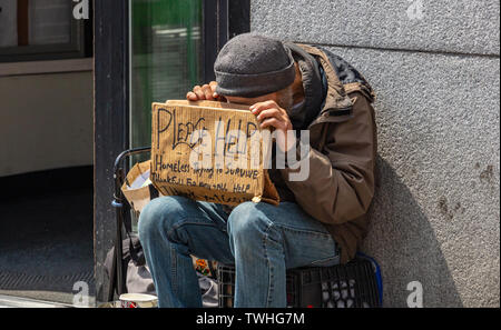 Etats Unis, New York. Le 2 mai 2019. Homeless man holding a sign en carton, demander de l'aide, le centre-ville de Manhattan, journée ensoleillée au printemps Banque D'Images