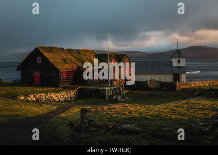 Noir et rouge typique des maisons en bois des îles Féroé avec toit d'herbe comme repéré pendant le coucher du soleil dans le village de Kirkjubour au printemps (îles Féroé) Banque D'Images