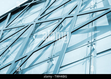 Résumé L'architecture commerciale, l'arrière-plan la façade de l'immeuble de bureau avec structure en acier et motif géométrique des panneaux de verre. Photo dans les tons bleus Banque D'Images