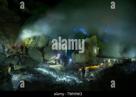 Les travailleurs des mines de soufre Soufre toxiques dans la mienne la nuit, retour blue fire du volcan Ijen, Ijen, Java, Indonésie Banque D'Images