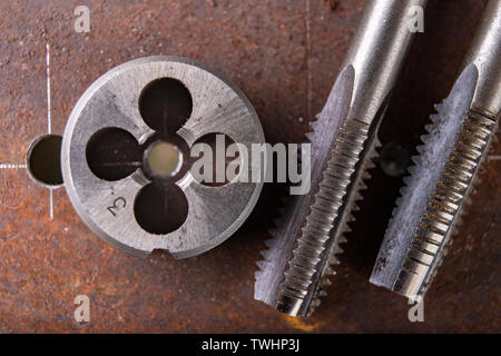 Filetage manuel en métal. Accessoires de serrurerie pour les petits travaux dans l'atelier de maison. Fond sombre. Banque D'Images