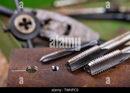 Filetage manuel en métal. Accessoires de serrurerie pour les petits travaux dans l'atelier de maison. Fond sombre. Banque D'Images