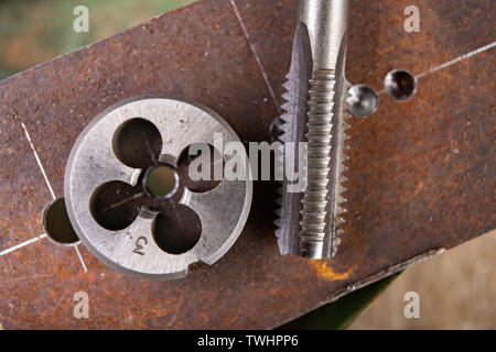 Filetage manuel en métal. Accessoires de serrurerie pour les petits travaux dans l'atelier de maison. Fond sombre. Banque D'Images