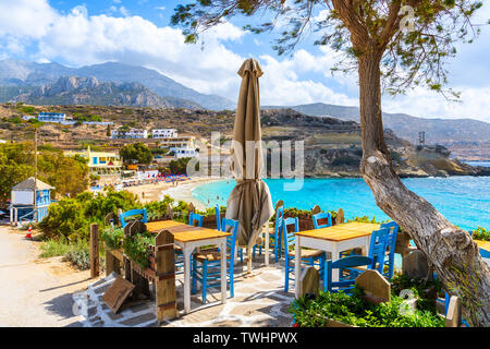 Taverna tables sur une terrasse et vue sur belle plage de Lefkos village sur la côte de l'île de Karpathos, Grèce Banque D'Images