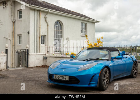 EV charge Irlande Blue 2010 Tesla Roadster voiture électrique comme charge étant chargée à l'extérieur par une maison privée à Kinsale, comté de Cork, Irlande Banque D'Images