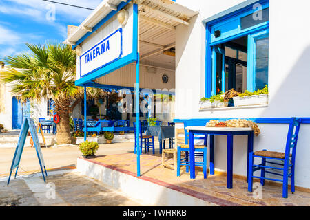 Table en face de taverne grecque typique sur la rue de village de Finiki, l'île de Karpathos, Grèce Banque D'Images