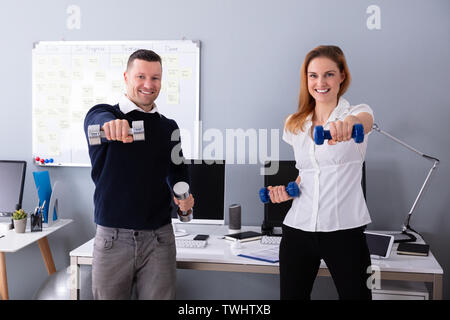 Close-up de l'homme et de la femme d'affaires de l'exercice en exercice avec haltères Banque D'Images