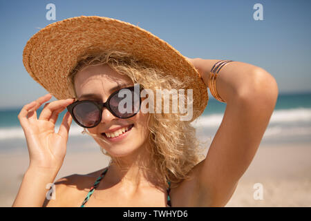 Femme au chapeau et des lunettes à la caméra à sur la plage Banque D'Images