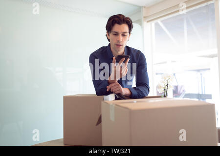 Male executive talking on mobile phone in office Banque D'Images