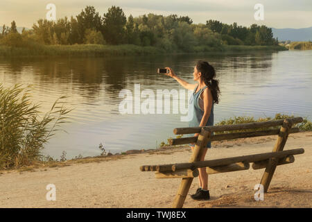 Jeune femme brune photographier un paysage avec rivière au coucher du soleil. La rivière Tajo, Espagne Banque D'Images