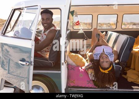 Couple looking at camera dans le camping-car at beach Banque D'Images
