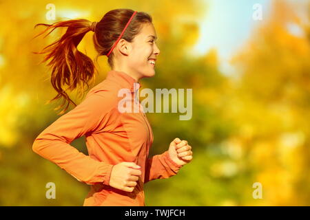 Woman runner fonctionnant en automne forêt d'automne. Femme fitness petite fille jogging le chemin en automne feuillage étonnant paysage nature extérieur. Banque D'Images