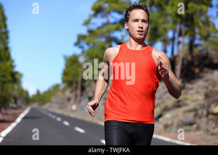 Sprint runner homme qui court à la vitesse rapide. Le sport masculin formation sprinter dur. Les jeunes hommes forts du modèle de remise en forme lors de l'exécution en plein air dans le magnifique paysage. Banque D'Images