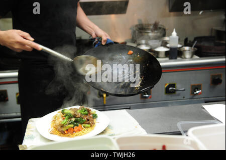 Close up of chef le placage et nouilles sur une assiette d'un wok, cuisine asiatique, chinois à emporter, cuisine. Banque D'Images