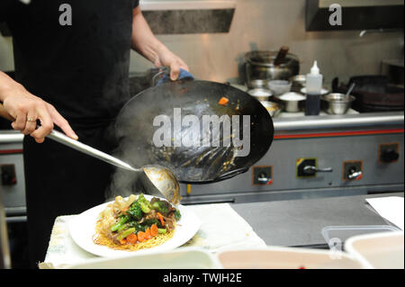 Close up of chef le placage et nouilles sur une assiette d'un wok, cuisine asiatique, chinois à emporter, cuisine. Banque D'Images