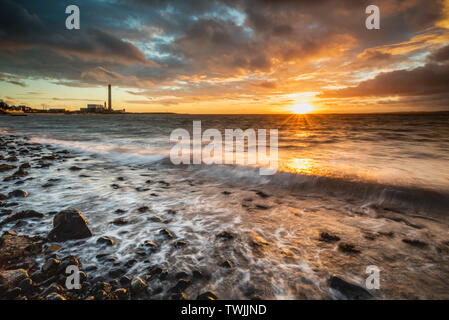 L'aube sur la plage de Downshire, Carrickfergus, l'Irlande du Nord à Kilroot Power Station dans la distance. Banque D'Images