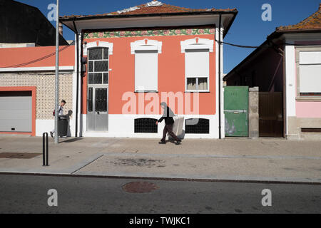 Delivery man se promenant dans la rue passé une maison rose avec des volets portant une boîte en polystyrène en Matosinhos Porto Portugal, Europe UE KATHY DEWITT Banque D'Images