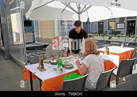 Young waiter serving couple plus âgé en plein air au restaurant de fruits de mer manger assis à table de repas manger du poisson en Matosinhos Porto Portugal KATHY DEWITT Banque D'Images