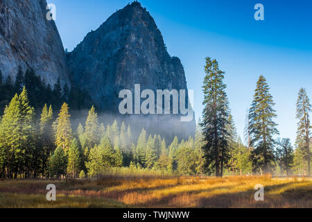 Une vue sur le magnifique paysage du canyon à Yosemite National Park, USA contre un beau ciel bleu et de la brume accrochent aux arbres Banque D'Images