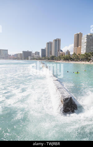 Les vagues frapper la digue tandis que les touristes et les habitants de marche sur elle à Kuhio Beach Park dans la plage de Waikiki, Oahu, Hawaii. Banque D'Images