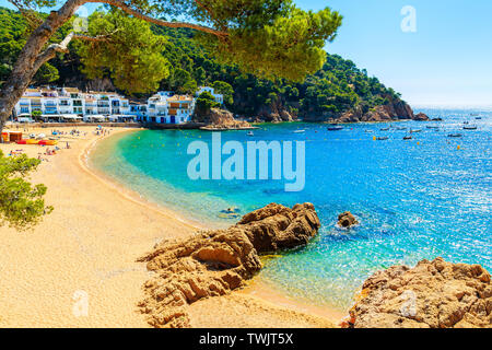 Jeune femme assise sur un rocher à très grande plage de sable à Tamariu ville en bord de mer, Costa Brava, Espagne Banque D'Images