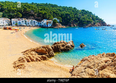 Jeune femme assise sur un rocher à très grande plage de sable à Tamariu ville en bord de mer, Costa Brava, Espagne Banque D'Images