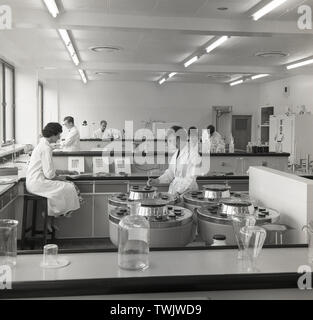 Années 1950, historiques, scientifiques, hommes et femmes au travail dans un brighly allumé, moderne, construit pour être un laboratoire de l'chemcial Sandoz, fabricants de teintures à Horsforth, Leeds, Angleterre, Royaume-Uni. Les tests employés sont des colorants chemcial pour utilisation dans le secteur du textile et du papier. Banque D'Images