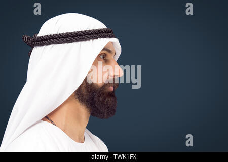 Portrait de mi-longueur de l'Arabian, homme bleu foncé sur fond de studio. Young male model posing et à de sérieux et de calme. Notion d'entreprise, des finances, de l'expression du visage, les émotions humaines. Banque D'Images