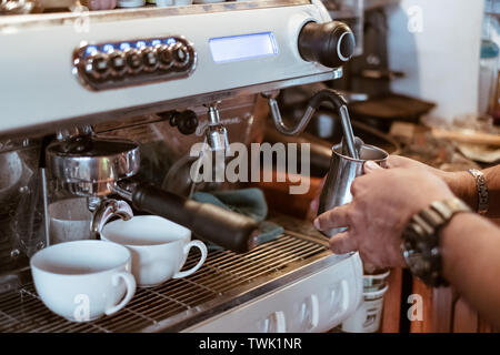 La vapeur de lait dans la main barista tasse à café métal sur bar Banque D'Images