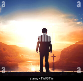 Businessman culte concept : successful businessman standing in front of cross Banque D'Images