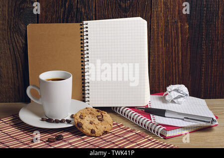 Ordinateur portable ouvert et du café noir avec les cookies sur la vieille table en bois Banque D'Images